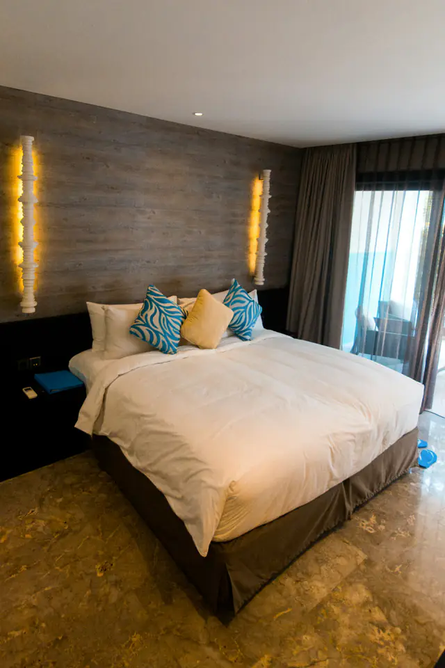 Villa bedroom with a white bed, teal cushions and warm wall lights